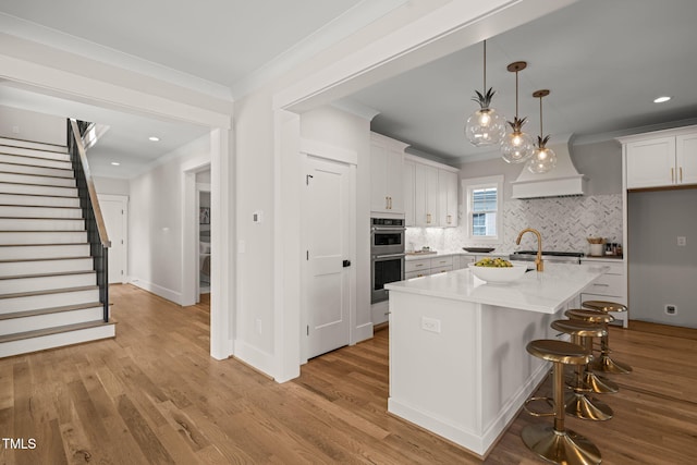 kitchen featuring white cabinetry, wood finished floors, tasteful backsplash, and ornamental molding