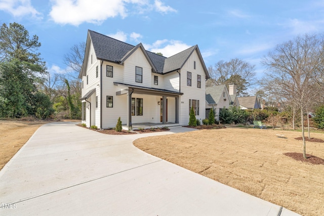 modern farmhouse style home featuring a porch, a garage, board and batten siding, and driveway