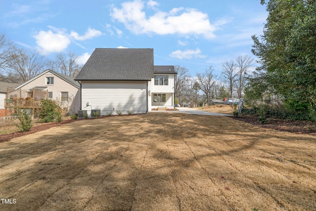 view of side of property with a lawn, central AC, and a shingled roof