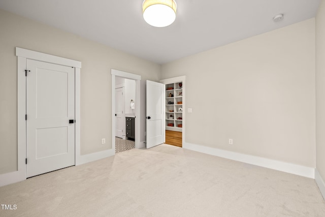 unfurnished bedroom featuring carpet flooring, connected bathroom, and baseboards