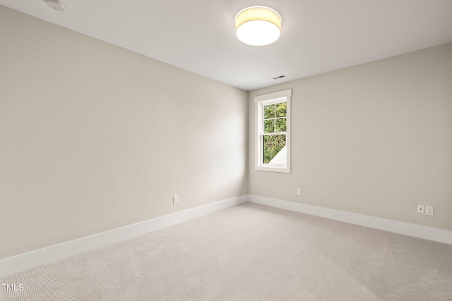 empty room featuring visible vents, light colored carpet, and baseboards