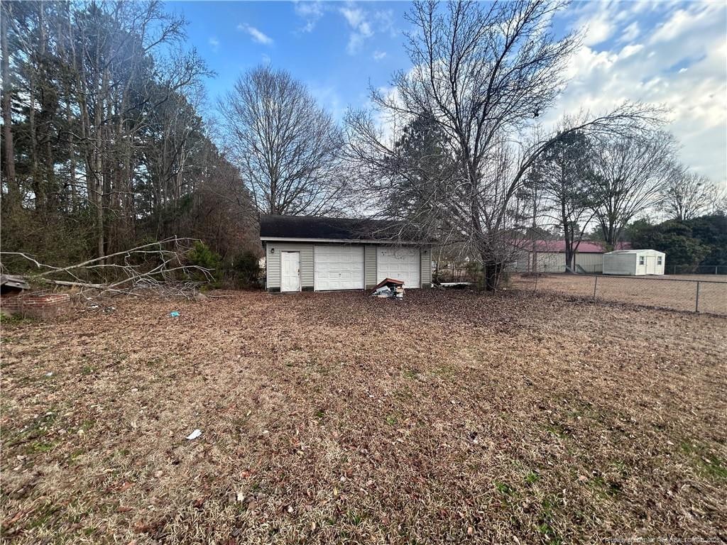 view of yard featuring a detached garage, fence, and an outdoor structure