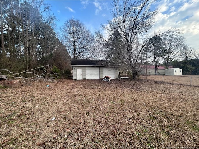 view of yard featuring a detached garage, fence, and an outdoor structure