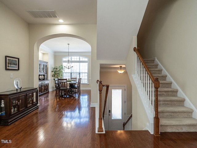 foyer entrance with dark wood finished floors, visible vents, an inviting chandelier, baseboards, and stairs