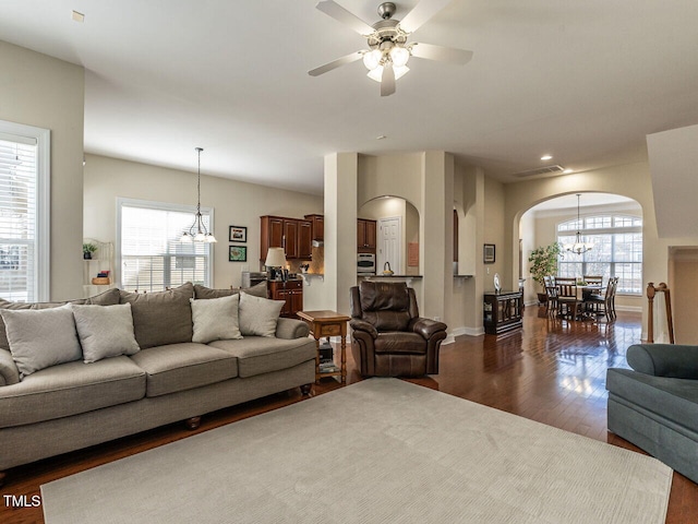 living room with arched walkways, a healthy amount of sunlight, dark wood finished floors, and visible vents