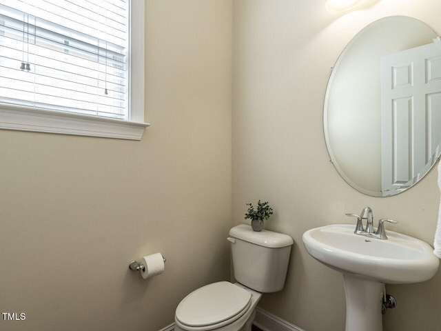 half bathroom featuring toilet and baseboards