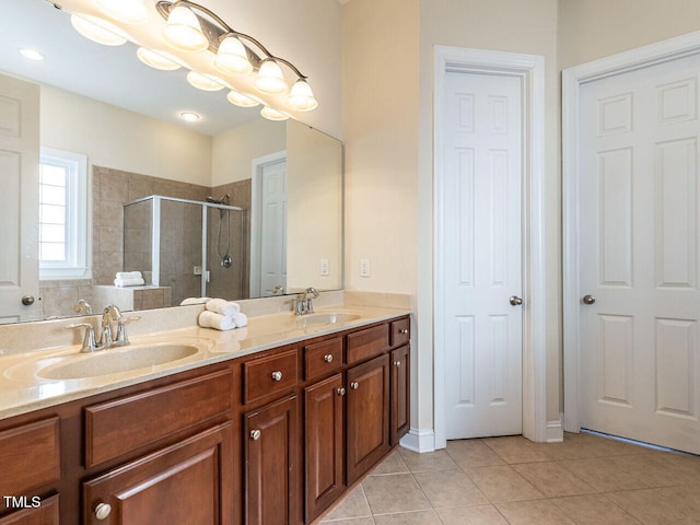 full bath featuring double vanity, a sink, a shower stall, and tile patterned floors