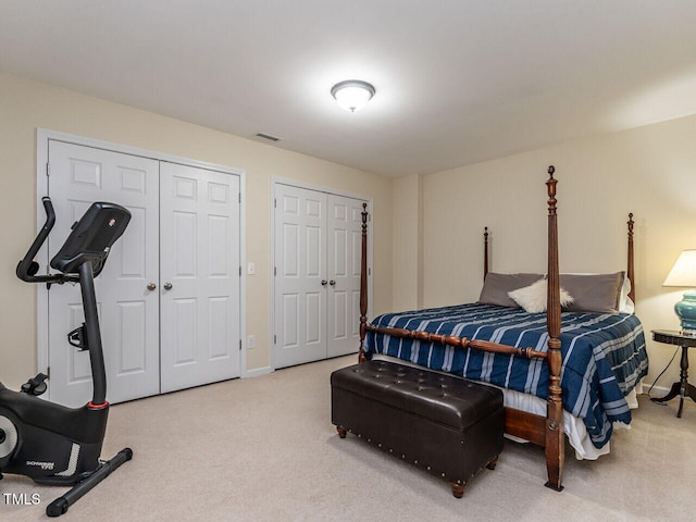 bedroom featuring carpet floors, baseboards, visible vents, and multiple closets