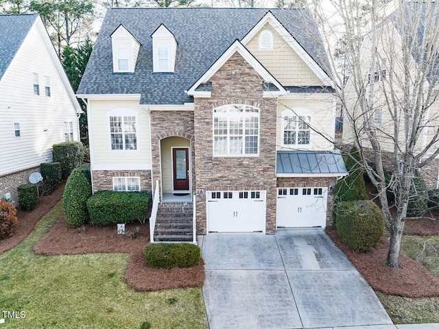 raised ranch with a shingled roof, concrete driveway, metal roof, a garage, and stone siding