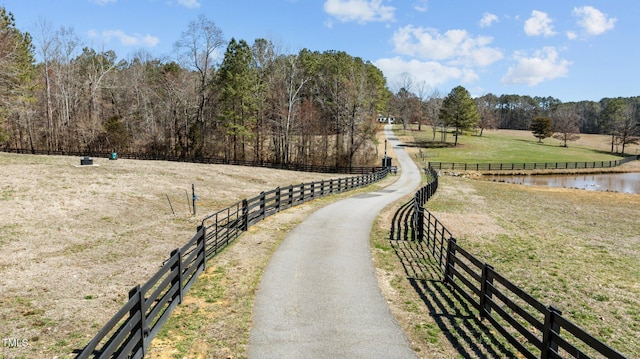 surrounding community featuring a rural view, a water view, fence, and a lawn