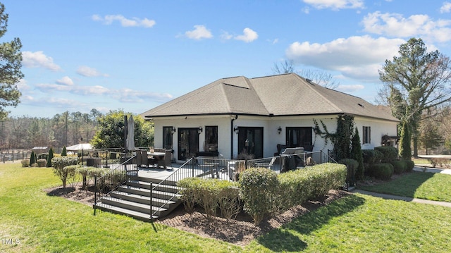 rear view of property featuring a yard, a shingled roof, a wooden deck, and brick siding