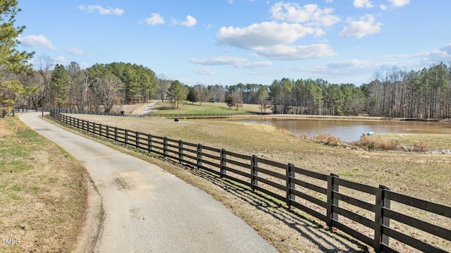 view of road featuring a water view, a wooded view, and a rural view