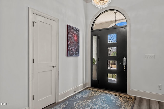 entrance foyer featuring baseboards, a chandelier, and wood finished floors