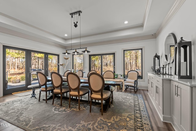 dining area with crown molding, a tray ceiling, and dark wood finished floors