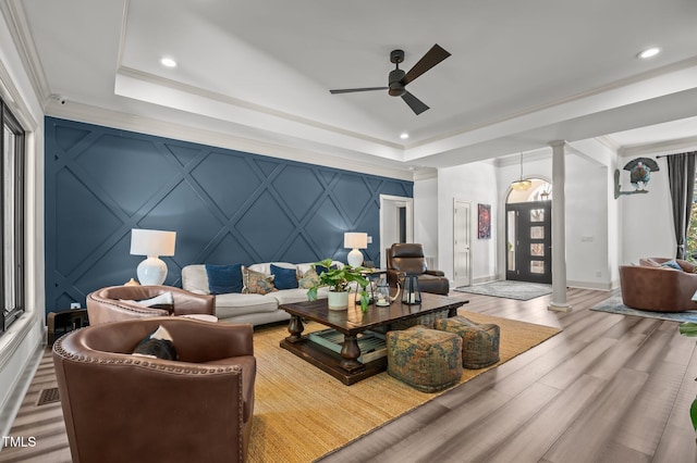 living area featuring decorative columns, a decorative wall, wood finished floors, and a raised ceiling