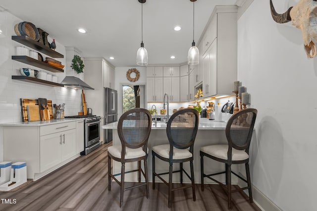 kitchen featuring hanging light fixtures, backsplash, dark wood-type flooring, gas range, and a peninsula