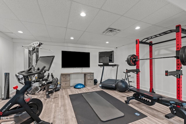 exercise room with a paneled ceiling, visible vents, wood finished floors, and recessed lighting