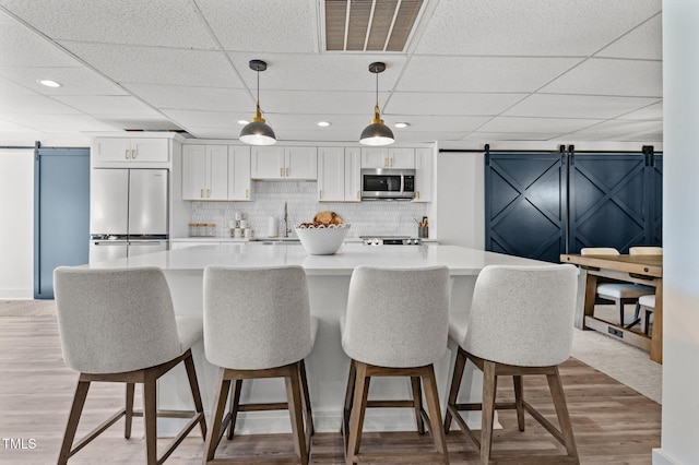 kitchen with a barn door, visible vents, white cabinetry, appliances with stainless steel finishes, and a center island