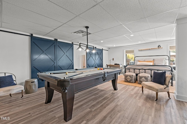 game room featuring a barn door, a drop ceiling, pool table, wood finished floors, and visible vents