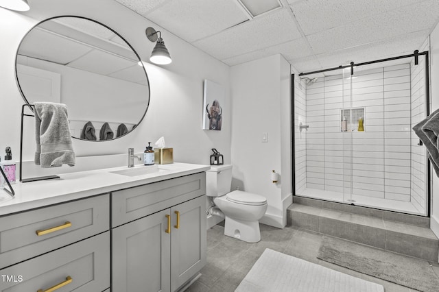 bathroom with a stall shower, a drop ceiling, vanity, and toilet