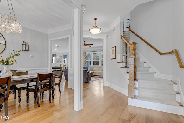 dining room with light wood-type flooring, an inviting chandelier, stairs, and crown molding