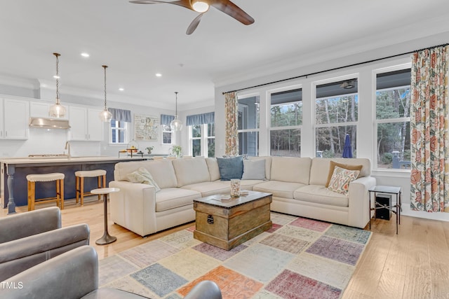 living area featuring ornamental molding, recessed lighting, light wood-style flooring, and a ceiling fan