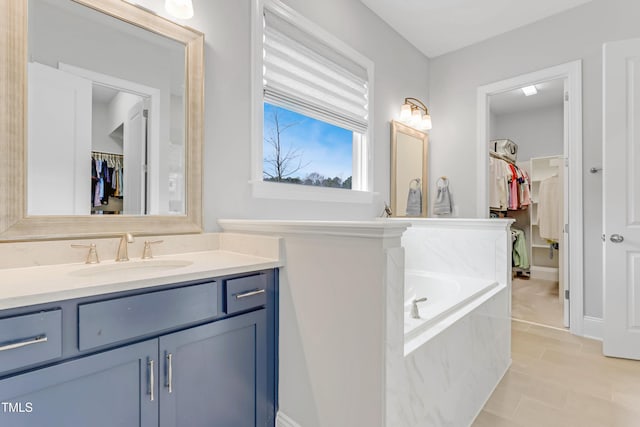 full bath featuring a spacious closet, a garden tub, and vanity