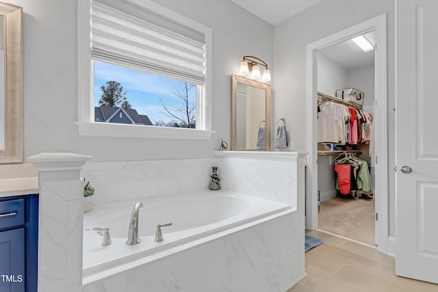 bathroom featuring a garden tub, tile patterned flooring, a walk in closet, and vanity