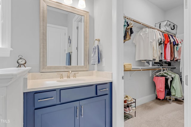 full bath featuring baseboards, a walk in closet, and vanity