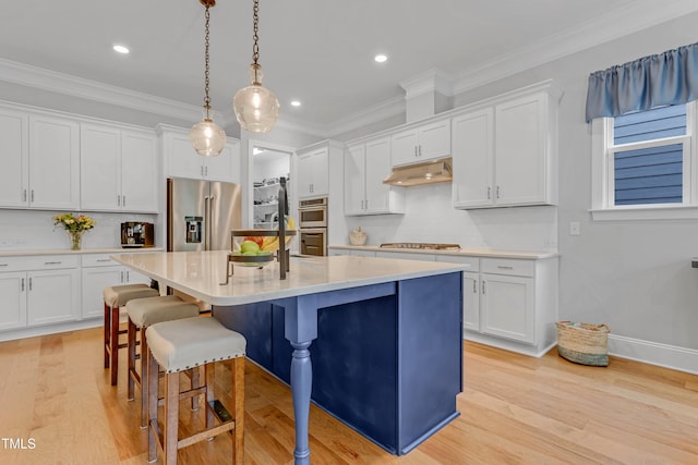 kitchen with a kitchen breakfast bar, a kitchen island with sink, stainless steel appliances, crown molding, and under cabinet range hood