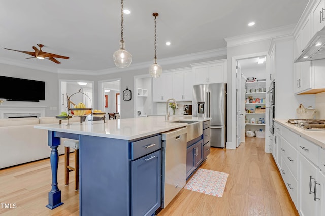 kitchen with a breakfast bar area, blue cabinetry, appliances with stainless steel finishes, open floor plan, and white cabinetry