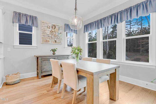 dining space with baseboards, crown molding, and light wood-style floors