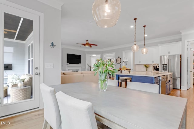 dining room featuring ornamental molding, light wood-style flooring, and a ceiling fan