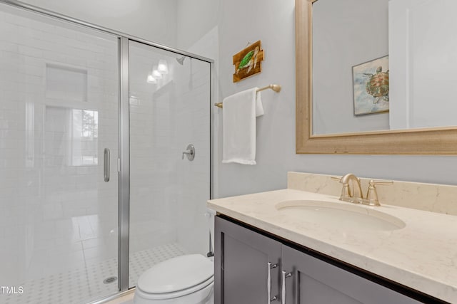 bathroom with vanity, a shower stall, and toilet