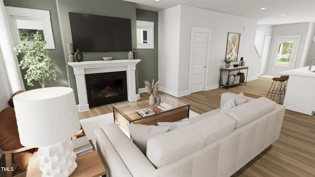 living room with recessed lighting, baseboards, a glass covered fireplace, and wood finished floors