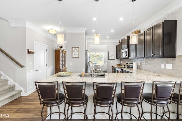 kitchen with dark wood-style floors, crown molding, tasteful backsplash, appliances with stainless steel finishes, and a sink