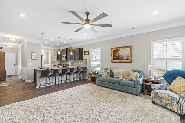 living room featuring a healthy amount of sunlight, dark wood-style floors, and crown molding