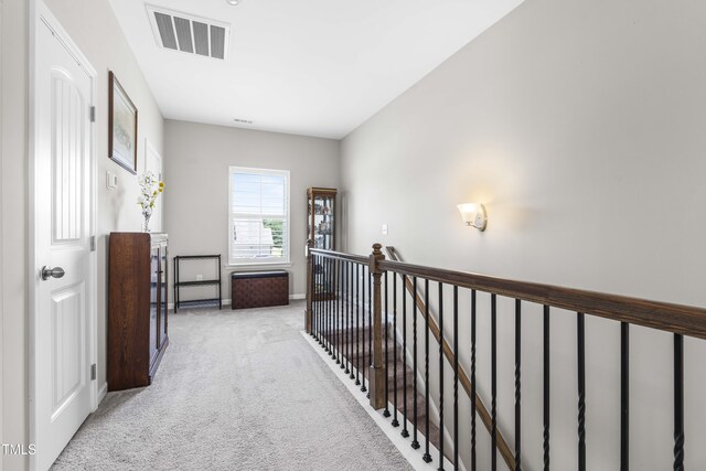 corridor featuring light carpet, an upstairs landing, visible vents, and baseboards