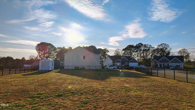 view of yard featuring a shed, an outdoor structure, a fenced backyard, and a residential view