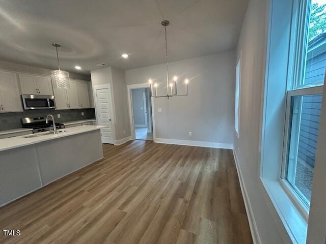 504 Yeowell Dr, Chapel Hill, NC 27514 - kitchen with appliances with stainless steel finishes, light countertops, a chandelier, decorative backsplash, and wood finished floors