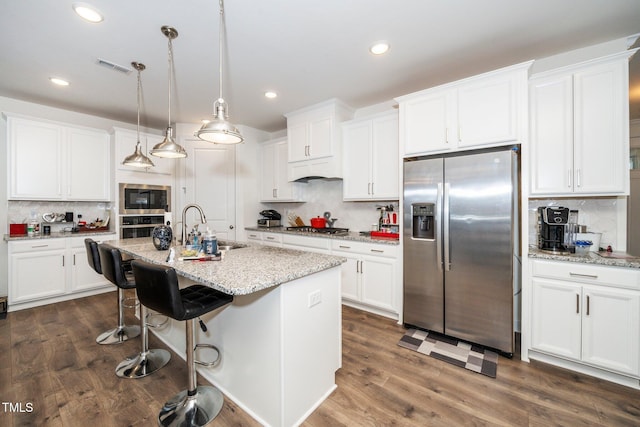 kitchen with stainless steel appliances, a sink, white cabinetry, and decorative light fixtures