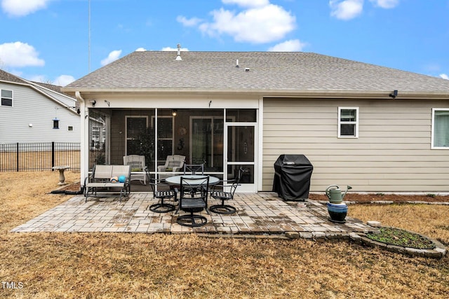 rear view of house with a shingled roof, a patio, a sunroom, fence, and a yard