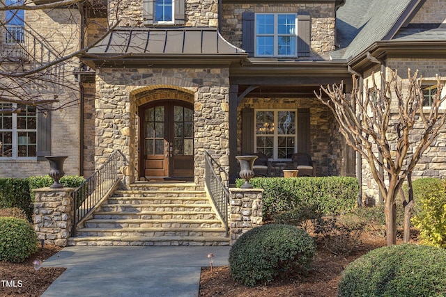 view of exterior entry with a shingled roof, a standing seam roof, and metal roof