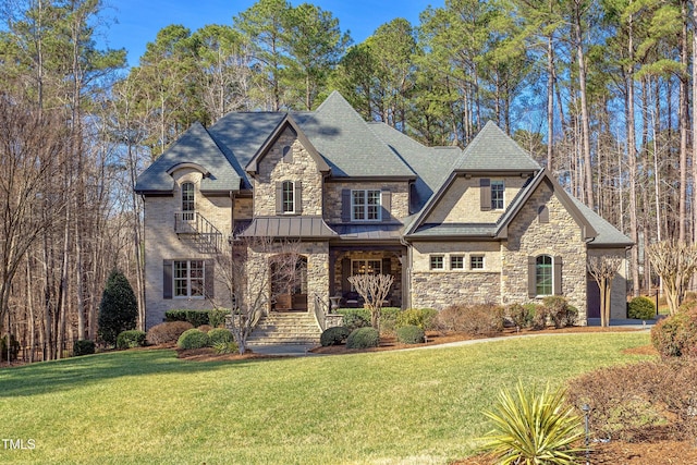 view of front of house featuring a standing seam roof, stone siding, metal roof, and a front yard