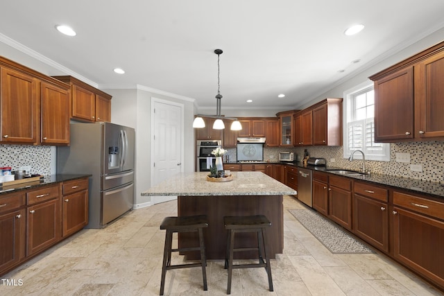 kitchen featuring pendant lighting, appliances with stainless steel finishes, glass insert cabinets, a kitchen island, and a sink