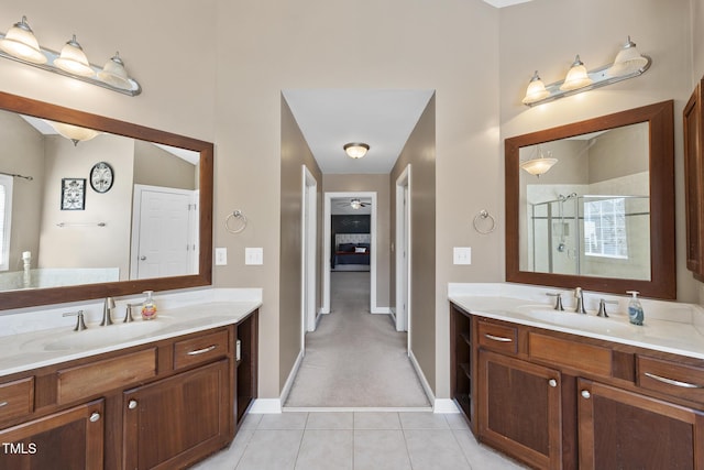 bathroom with a stall shower, tile patterned flooring, two vanities, and a sink