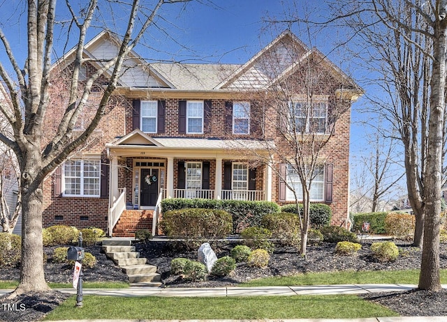 view of front of property with covered porch, brick siding, and crawl space