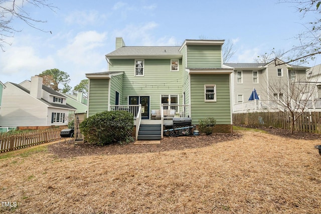 rear view of house with fence, a chimney, and a wooden deck