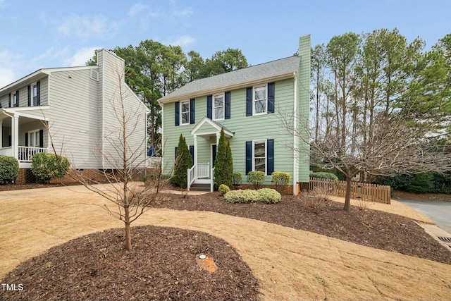 colonial house featuring fence and a chimney