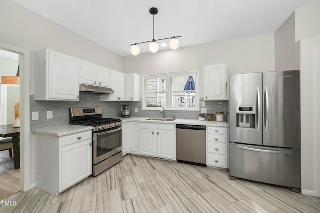 kitchen featuring tasteful backsplash, light countertops, appliances with stainless steel finishes, a sink, and under cabinet range hood